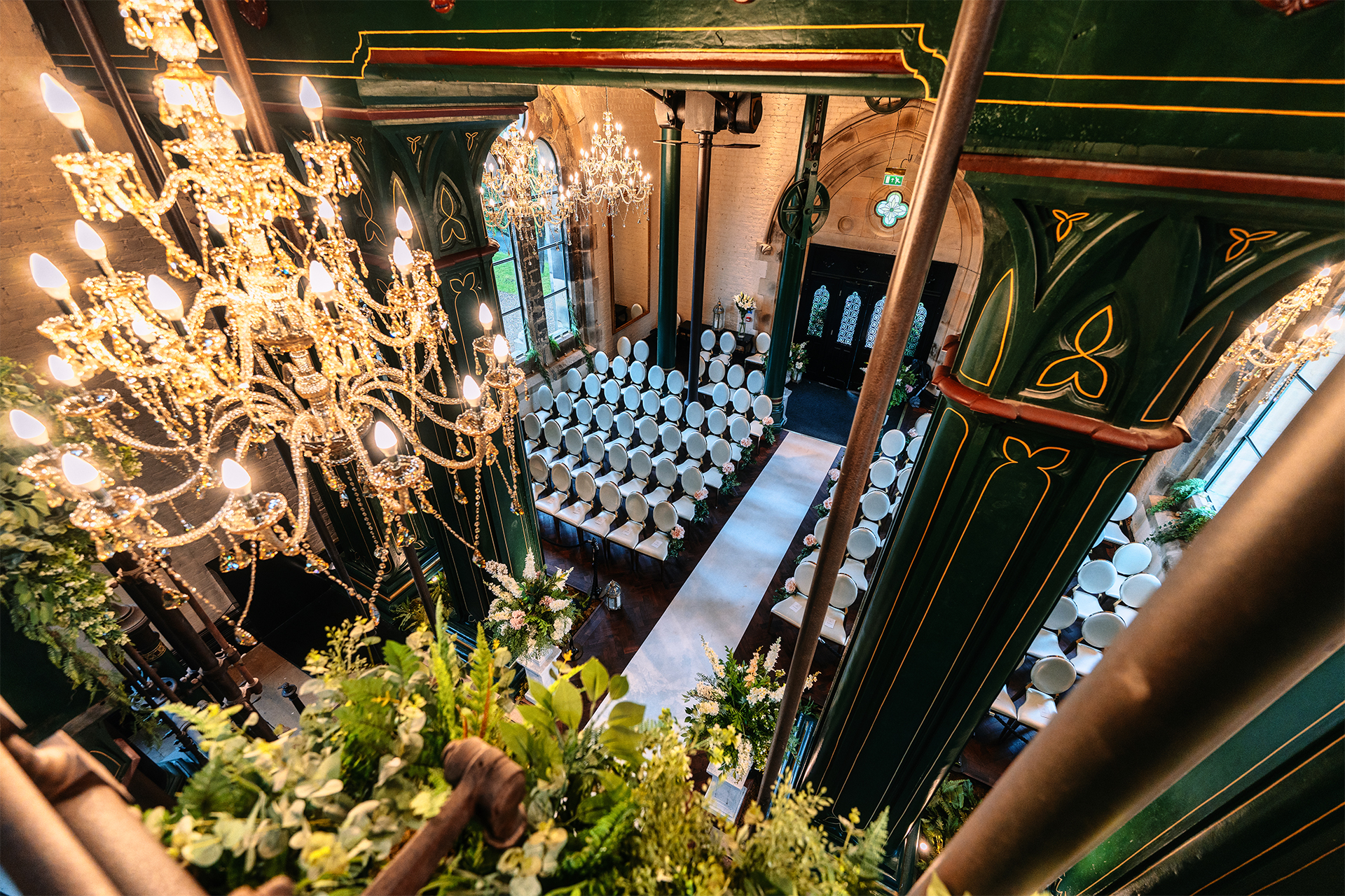 Overhead view of a wedding ceremony aisle with chandeliers and green columns at Dalton Old Pump House