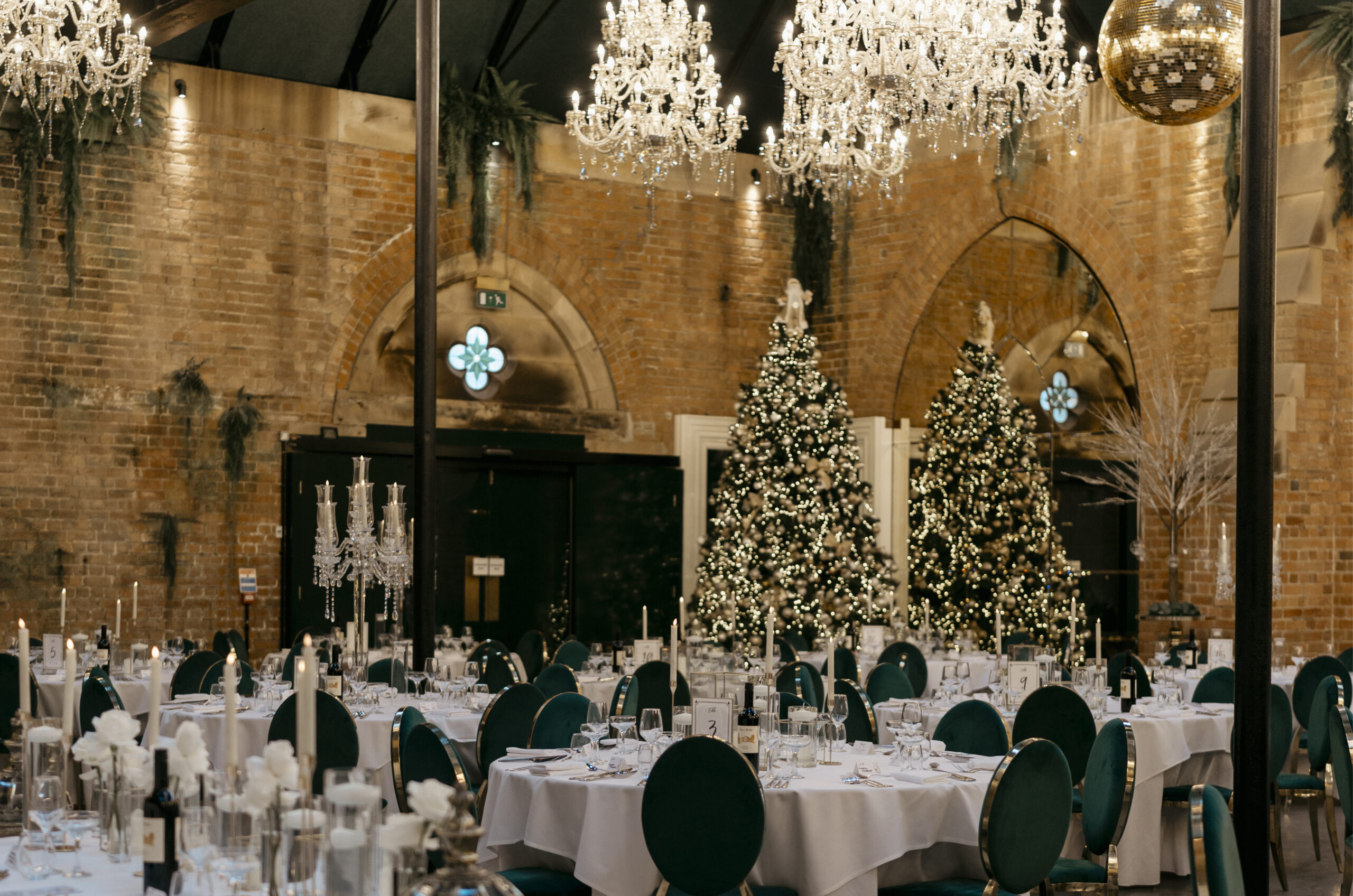 Christmas wedding breakfast set-up with green velvet chairs and lit trees at Dalton Old Pump House